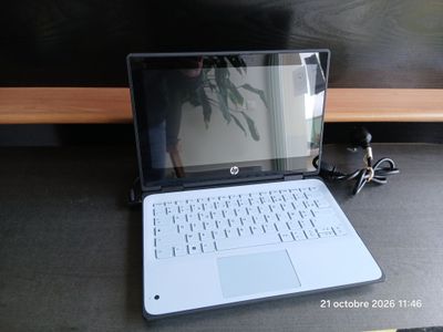 un ordinateur portable posé sur un bureau, à côté d'une plante