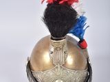 un casque doré orné de plumes rouges et bleues