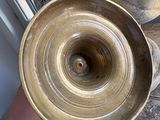 a person holding a brass bowl in their hand