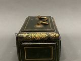 an old black and gold box sitting on top of a table