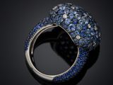 a close up of a ring with blue sapphires on a black surface