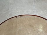 a wooden bowl sitting on the floor with a knife in it