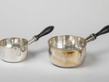 pair of silver saucepans with black handles on a white background