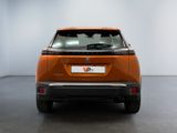the rear end of an orange electric car in a white room