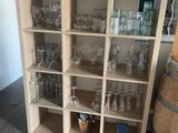 des bouteilles et des verres posés sur une étagère dans une pièce où se trouve un tonneau de vin