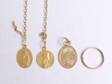 three gold coin necklaces and a gold ring on a white surface