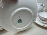 a person holding a tea pot and a tea cup on a table