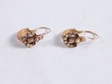 a pair of gold earrings with brown stones on a white surface