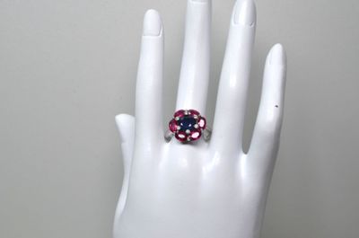 une main blanche ornée d'une bague rose et bleue