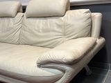 a white leather couch sitting on a rug in a room