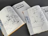 two open books with drawings of people on them sitting on a table