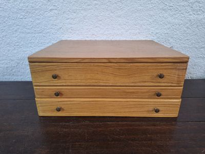une photo représentant une commode en bois à trois tiroirs posée sur une table