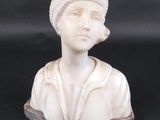 white marble bust of a woman with a hat on a black background