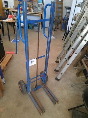 a blue hand truck with a sign on it in a garage