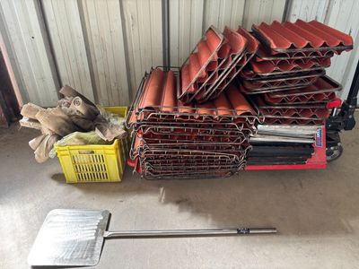 une pile de tuiles rouges sur un chariot à côté d'une pile d'autres tuiles