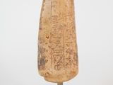 an old stone object with writing on it sitting on a stand