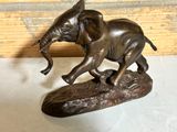 a statue of an elephant that is standing on a piece of wood