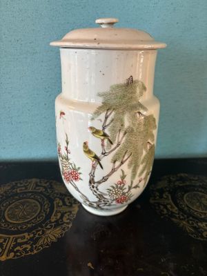 a white vase with birds on it sitting on a table