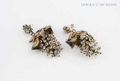 une paire de boucles d’oreilles ornées de perles, posées sur un fond blanc