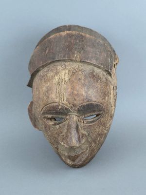 un vieux masque en bois au visage brun et coiffé d'un chapeau brun