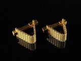 a pair of gold plated earrings on a black background