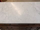 a white marble counter top sitting on top of a wooden cabinet