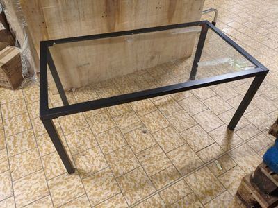 une table en verre surmontée d'un piètement métallique