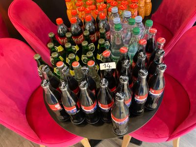 many bottles of soda sitting on a table in a room