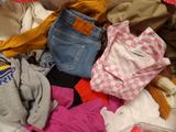 a pile of clothes that is sitting on a bed