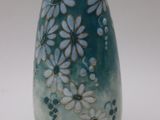 un vase bleu orné de fleurs blanches, posé sur une surface blanche
