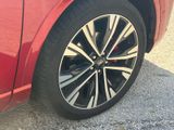 a close up of a red car ' s wheel on the road
