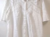 une chemise blanche suspendue à un mur à l'aide d'un cintre en bois