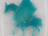 une image représentant un cheval en plastique bleu posé sur une assiette blanche