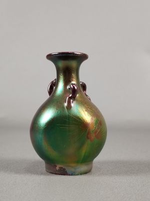 un vase vert orné d'un oiseau, posé sur une table