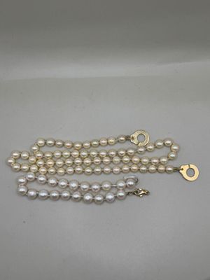 a close up of a white pearl necklace with a gold clasp