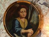 un tableau représentant une femme assise dans une pièce où l'on voit des paons accrochés au mur