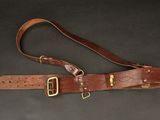 a brown leather belt with brass buckles on a black background