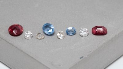 quatre pierres précieuses de couleurs différentes sont disposées en ligne sur une surface grise