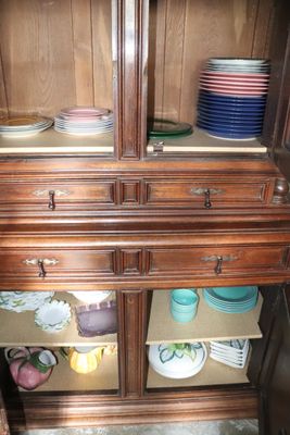 a wooden cabinet with many plates and bowls on top of it