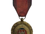 une ancienne médaille avec un ruban rouge sur fond blanc