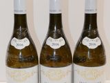 trois bouteilles de vin sont alignées sur une surface blanche