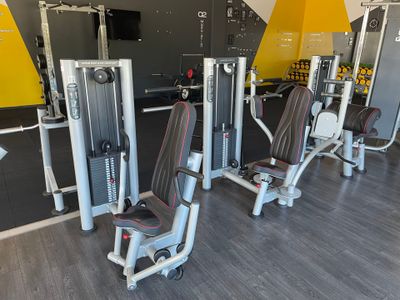 plusieurs appareils dans une salle de sport, avec un mur jaune en arrière-plan