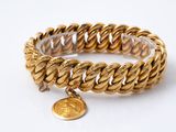 Gros plan sur un bracelet en or orné d'une pièce de monnaie