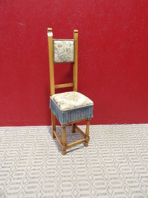 une petite chaise en bois avec un coussin dessus, devant un mur rouge