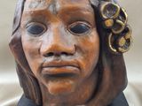 sculpture of a woman ' s head with a flower in her hair
