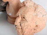 a clay sculpture of a woman ' s head next to a tree branch