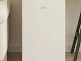 a small white refrigerator in the corner of a living room