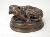 statue en bronze représentant un chien couché sur le dos sur un socle