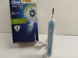 une brosse à dents électrique bleue et blanche à côté d'un tube de dentifrice
