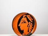 une assiette orange et noire sur laquelle est peint le visage d'une femme